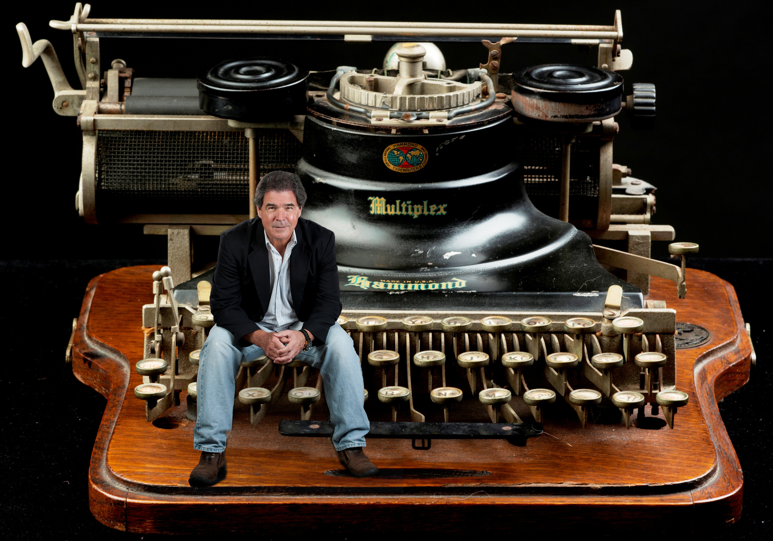 Michael J Griffin sitting on the keys of a vintage typewriter